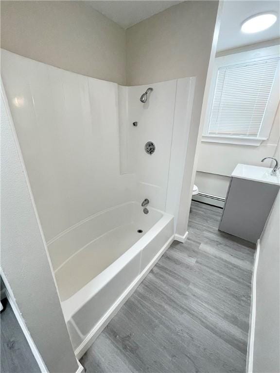 bathroom featuring baseboard heating, wood finished floors,  shower combination, and vanity