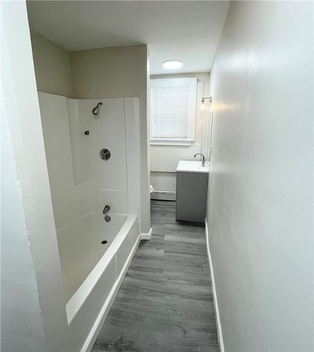 bathroom featuring wood finished floors, baseboard heating, baseboards, vanity, and shower / tub combination
