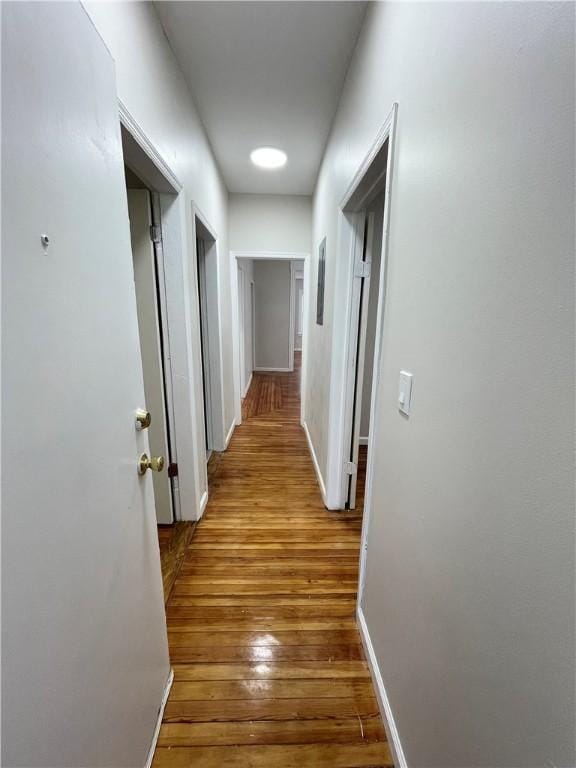 corridor featuring hardwood / wood-style floors and baseboards