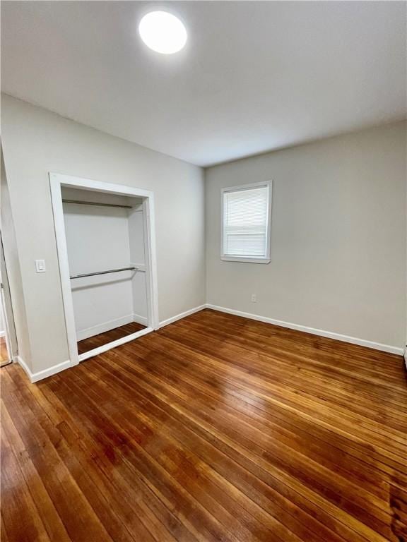 unfurnished bedroom with wood finished floors, baseboards, and a closet