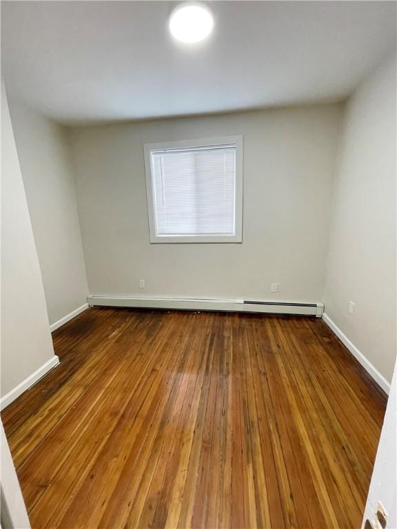 unfurnished room with baseboards and hardwood / wood-style floors