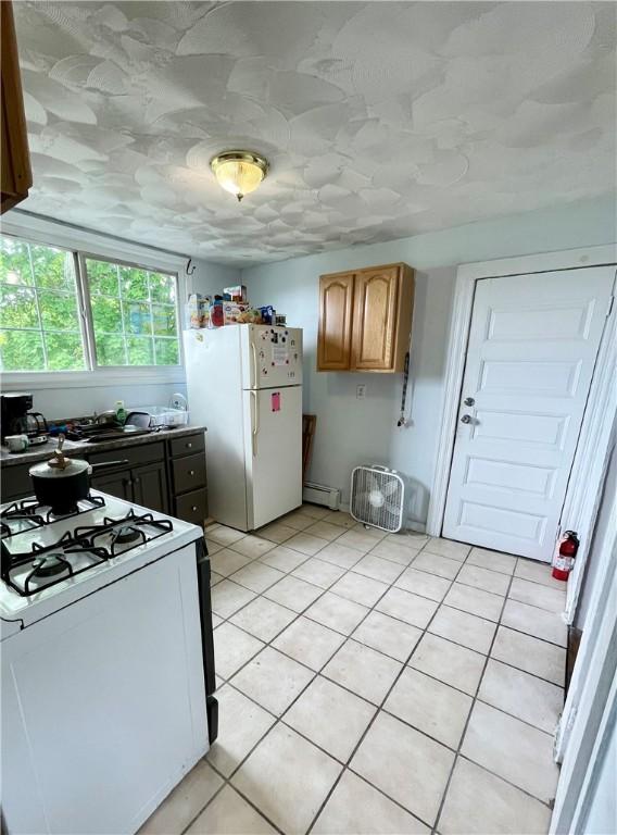 kitchen featuring white appliances, a baseboard radiator, and light tile patterned floors