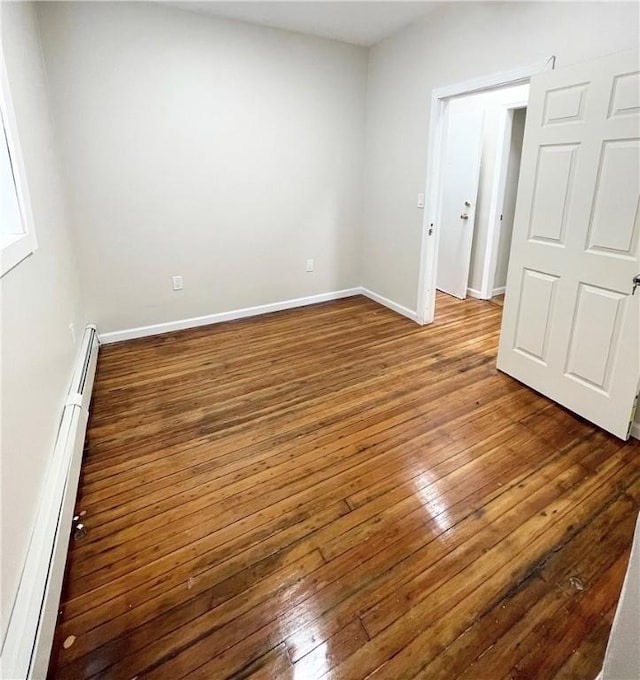 unfurnished bedroom featuring wood-type flooring, a baseboard radiator, and baseboards