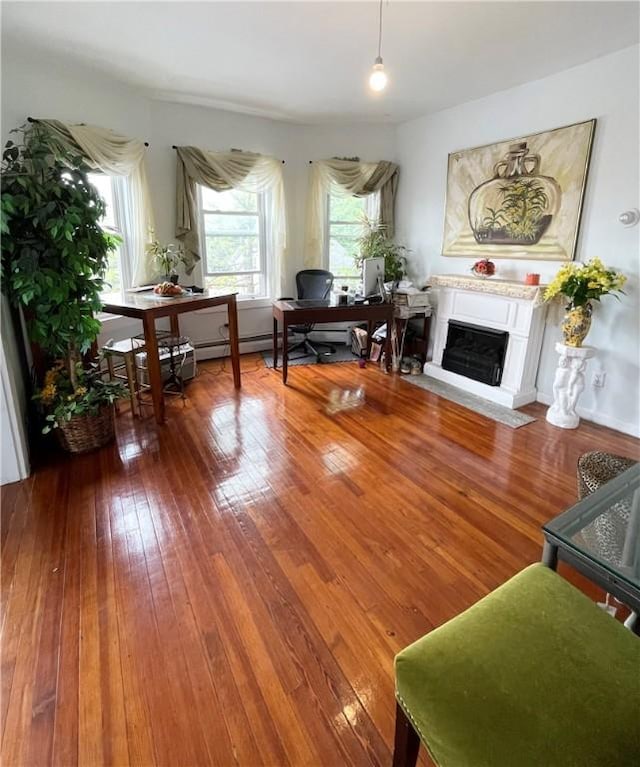 living area featuring wood-type flooring, an office area, and a fireplace with flush hearth