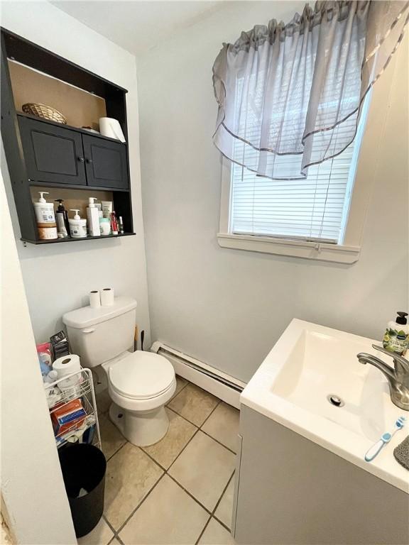 bathroom with a baseboard heating unit, tile patterned flooring, toilet, and vanity
