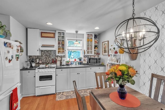1 Fried Ave, Bristol, RI 02809 - kitchen with white appliances, dark countertops, a chandelier, a sink, and glass insert cabinets
