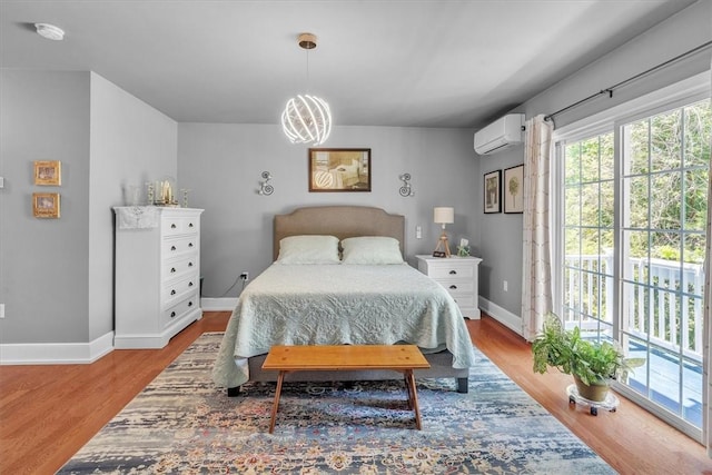 1 Fried Ave, Bristol, RI 02809 - bedroom featuring a wall unit AC, baseboards, wood finished floors, a chandelier, and access to exterior
