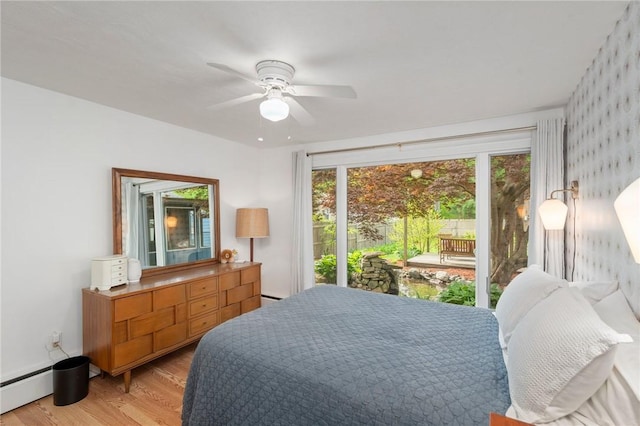 bedroom featuring multiple windows, light wood-style floors, ceiling fan, and a baseboard heating unit