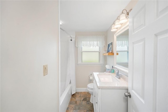 bathroom with stone finish floors, vanity, toilet, baseboards, and shower / tub combo with curtain