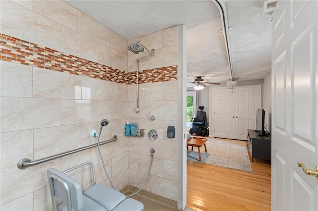 full bathroom with tiled shower, wood finished floors, and a ceiling fan