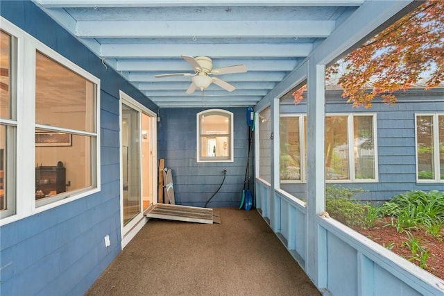 unfurnished sunroom featuring a ceiling fan and beam ceiling