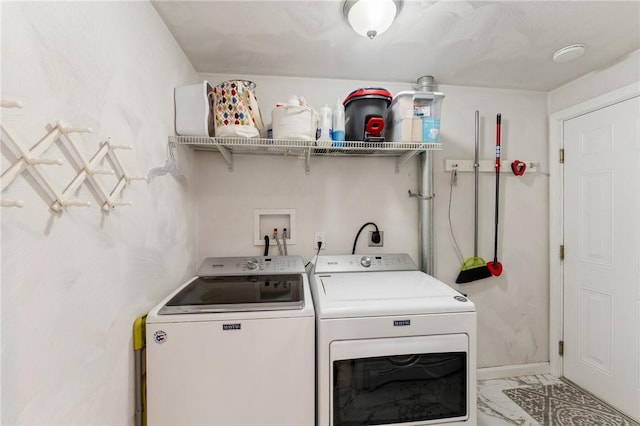 washroom with marble look tiles, washing machine and clothes dryer, and baseboards