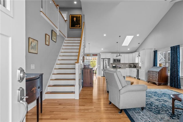 9 Thelma Ln, Middletown, RI 02842 - living area featuring high vaulted ceiling, a skylight, stairs, light wood-type flooring, and recessed lighting