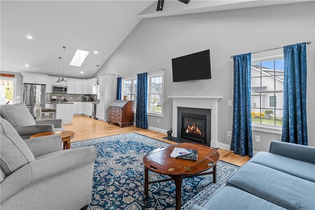 9 Thelma Ln, Middletown, RI 02842 - living room featuring high vaulted ceiling, a skylight, recessed lighting, a fireplace with flush hearth, and light wood-type flooring