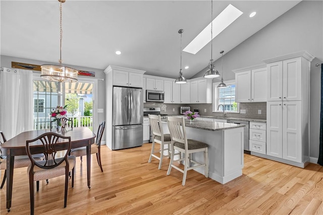 9 Thelma Ln, Middletown, RI 02842 - kitchen with stainless steel appliances, a skylight, a center island, white cabinetry, and backsplash
