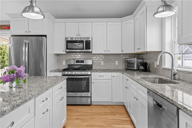 9 Thelma Ln, Middletown, RI 02842 - kitchen featuring appliances with stainless steel finishes, a sink, white cabinets, pendant lighting, and backsplash