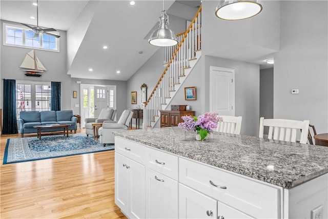 9 Thelma Ln, Middletown, RI 02842 - kitchen with a towering ceiling, light wood-style floors, light stone counters, plenty of natural light, and white cabinetry