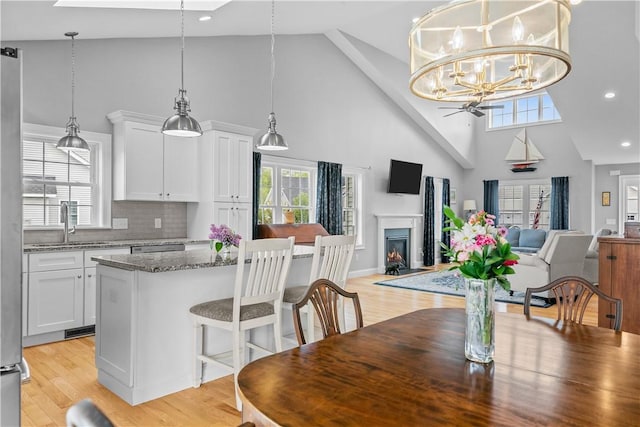 9 Thelma Ln, Middletown, RI 02842 - dining area with high vaulted ceiling, a lit fireplace, plenty of natural light, light wood-style flooring, and recessed lighting