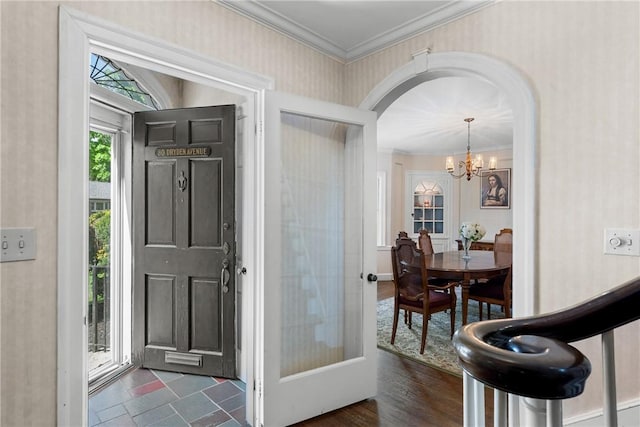 foyer entrance featuring arched walkways, a chandelier, and crown molding