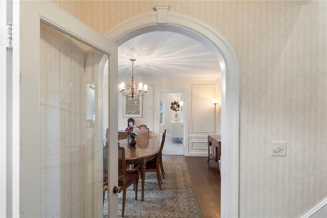 dining area featuring arched walkways, dark wood-style floors, and a chandelier