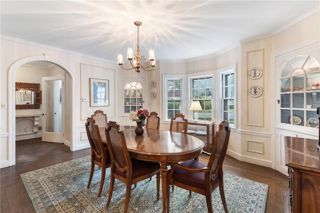 dining area featuring a chandelier, arched walkways, dark wood-style flooring, crown molding, and a decorative wall