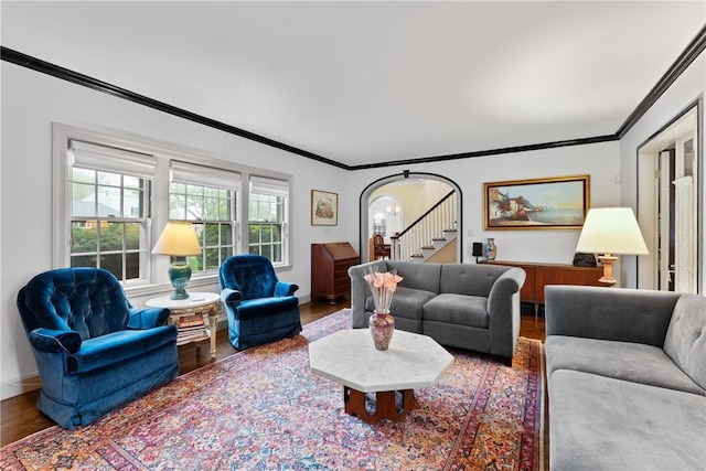living room featuring crown molding, wood finished floors, arched walkways, and baseboards