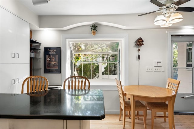dining area with light wood-style floors, plenty of natural light, and a ceiling fan