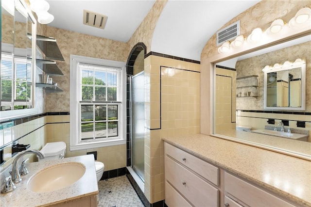 bathroom featuring tile walls, toilet, vanity, a shower stall, and tile patterned floors