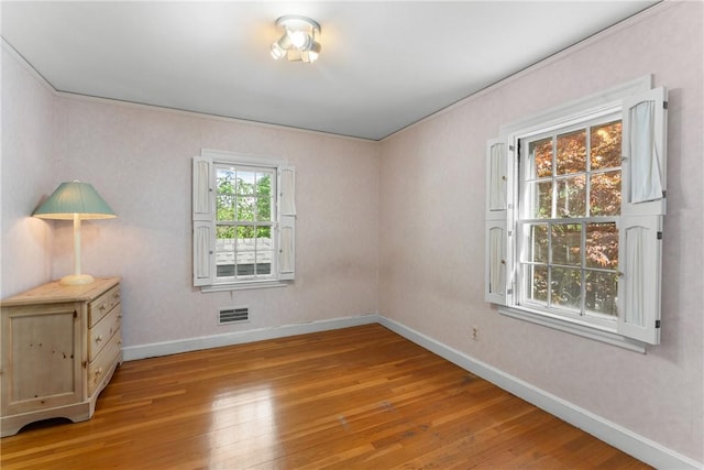 empty room with light wood-style floors, baseboards, and ornamental molding