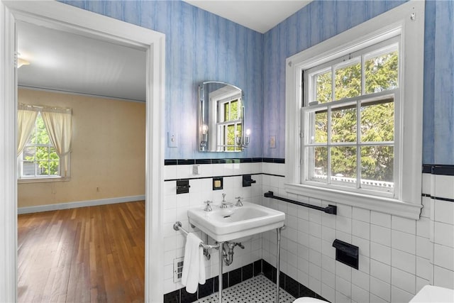 half bathroom featuring plenty of natural light, wallpapered walls, baseboards, and wood finished floors