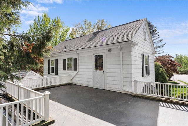 back of house featuring roof with shingles and a patio area