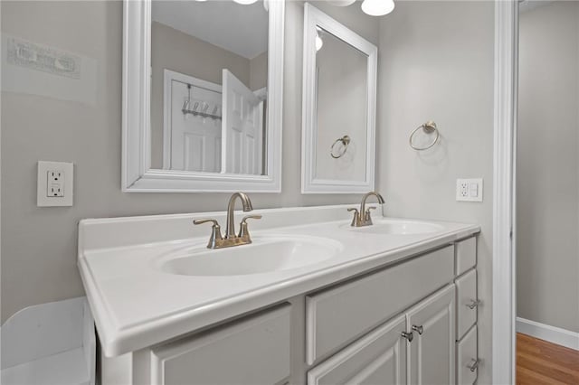 bathroom featuring double vanity, wood finished floors, and baseboards