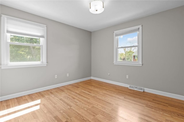 unfurnished room featuring healthy amount of natural light, light wood-style flooring, and baseboards