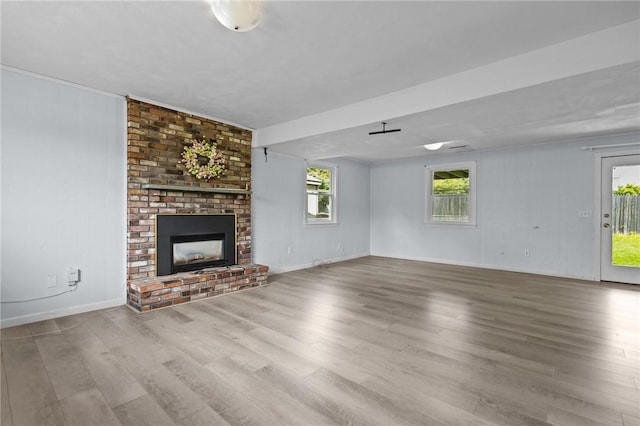 unfurnished living room with wood finished floors, a fireplace, and baseboards