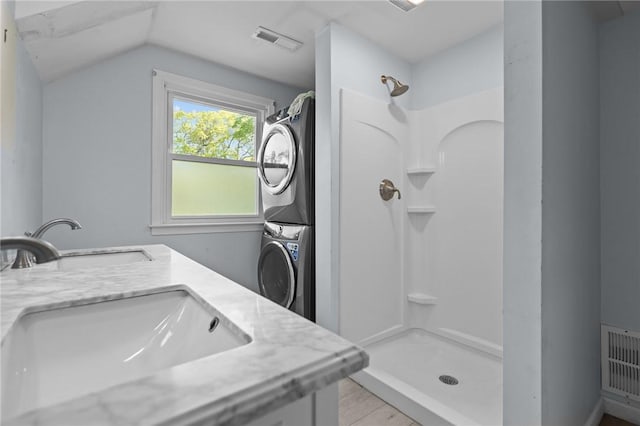 bathroom with estacked washer and dryer, a shower stall, lofted ceiling, and double vanity