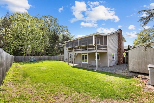 rear view of property featuring a sunroom, a storage unit, a chimney, an outdoor structure, and stairs