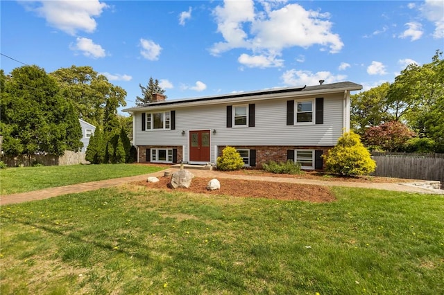 raised ranch featuring solar panels, a chimney, and brick siding