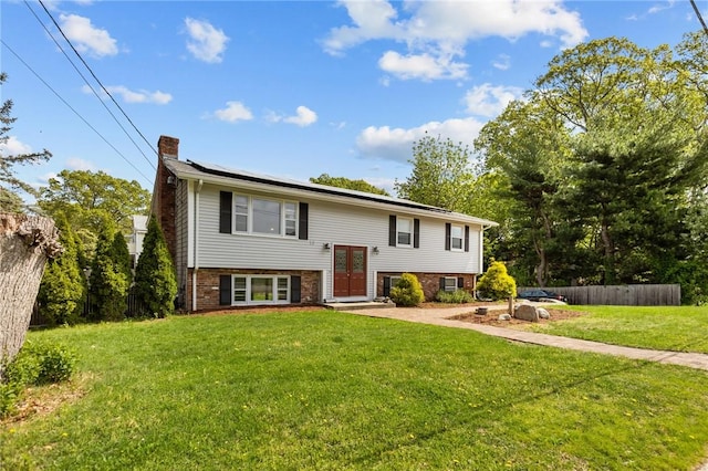 split foyer home with a chimney, solar panels, brick siding, and french doors