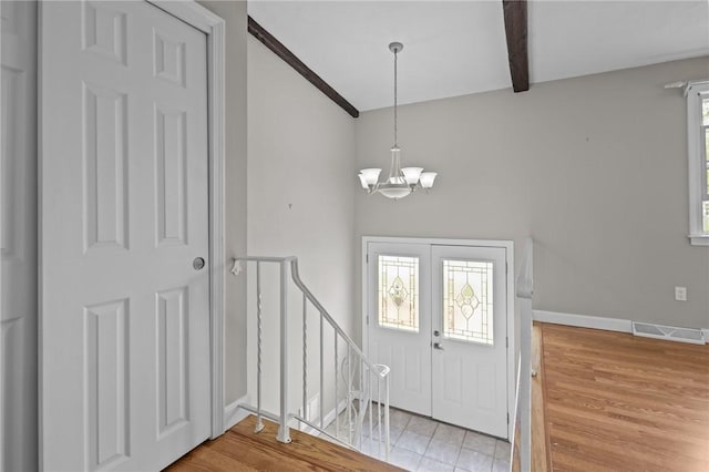 entrance foyer featuring a chandelier, beamed ceiling, baseboards, and wood finished floors