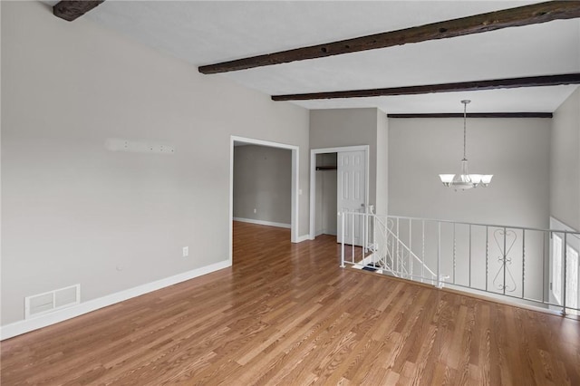 unfurnished room with a chandelier, light wood-style flooring, baseboards, and beam ceiling