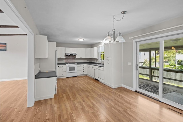kitchen with white appliances, under cabinet range hood, a sink, dark countertops, and baseboards