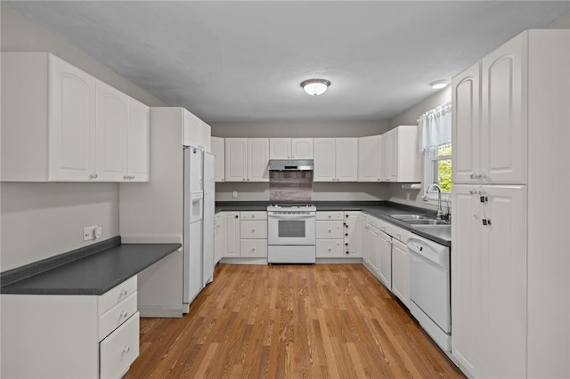 kitchen featuring white appliances, a sink, under cabinet range hood, dark countertops, and white cabinets
