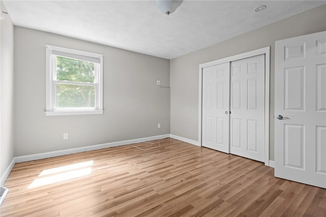 unfurnished bedroom with light wood-type flooring, baseboards, and a closet
