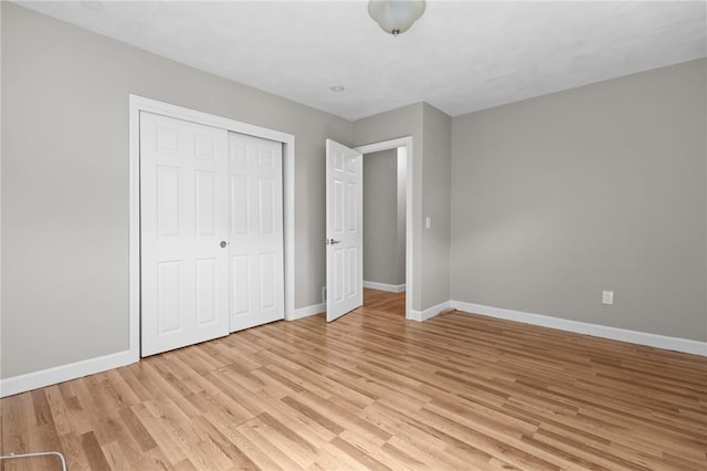 unfurnished bedroom with baseboards, light wood-type flooring, and a closet