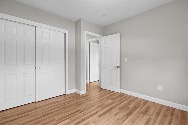 unfurnished bedroom with baseboards, light wood finished floors, and a closet