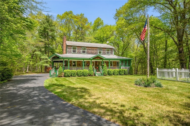 view of front of home with covered porch, driveway, and a chimney