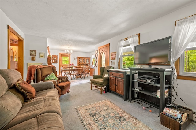 living area featuring a chandelier, light carpet, and a textured ceiling