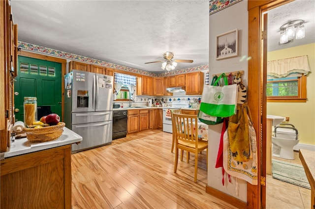 kitchen with stainless steel fridge, white electric range, dishwasher, under cabinet range hood, and brown cabinets