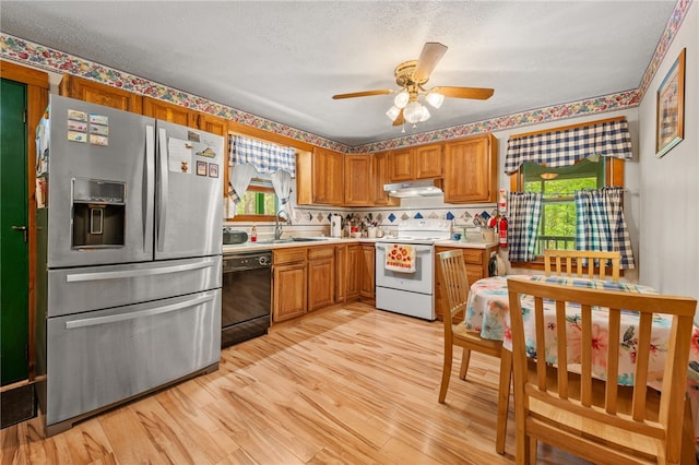 kitchen with stainless steel refrigerator with ice dispenser, white electric stove, dishwasher, under cabinet range hood, and a sink
