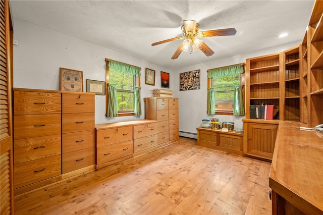 office area featuring baseboard heating, light wood-type flooring, and a ceiling fan